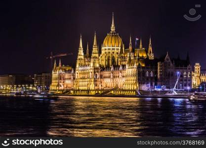 Budapest Parliament in Hungary at night, reflections on the Danube river waters.