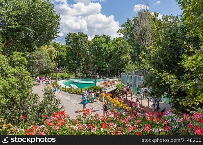 Budapest zoo with people at footpath surrounded with beautiful flowers - people with blurred faces. Budapest zoo with people at footpath surrounded with beautiful flowers