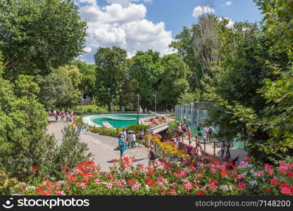 Budapest zoo with people at footpath surrounded with beautiful flowers - people with blurred faces. Budapest zoo with people at footpath surrounded with beautiful flowers