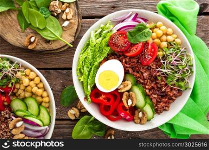Buddha bowl dish with boiled egg, chickpea, fresh tomato, sweet pepper, cucumber, savoy cabbage, red onion, green sprouts, spinach leaves, walnuts, chia and rice. Healthy lunch, dinner. Detox diet