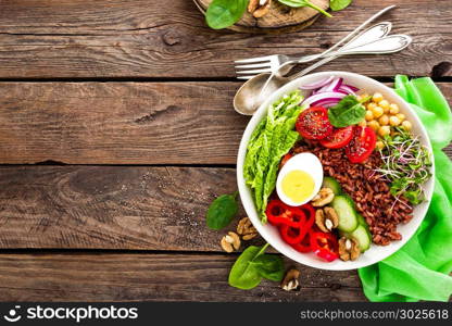 Buddha bowl dish with boiled egg, chickpea, fresh tomato, sweet pepper, cucumber, savoy cabbage, red onion, green sprouts, spinach leaves, walnuts, chia and rice. Healthy lunch, dinner. Detox diet