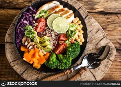 Buddha bowl salad with chicken fillet, brown rice, avocado, pepper, tomato, broccoli, red cabbage, chickpea, fresh lettuce salad, pine nuts and walnuts. healthy food. balanced diet eating. Top view