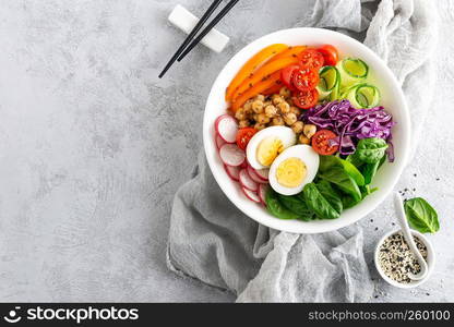 Buddha bowl salad with chickpeas, sweet pepper, tomato, cucumber, red cabbage kale, fresh radish, spinach leaves and boiled egg, healthy eating concept, top view, flat lay