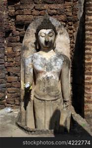 Buddha near brick wall in wat Phra Si Ratana Mahaphat, Si Satchanalai, Thailand