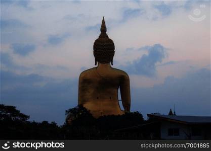 Buddha with architecture in field at blue sky.