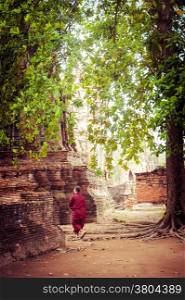 Buddhist monk at ancient ruins of Wat Mahathat. Ayutthaya, Thailand travel landscape and destinations. Vintage style image