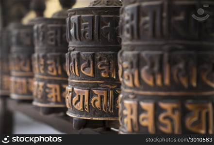 Buddhist obsolete prayer wheels in row with artistic shallow DOF in Nepal