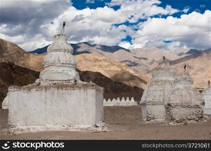 Buddhist stupa ( chorten ) over Himalaya high mountain landscape with cloudy blue sky India, Ladakh, Leh valley