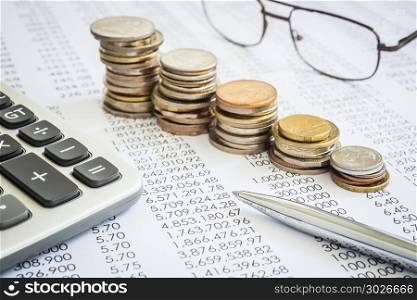 Budget and tax planning with raising coin stacks.. Closeup the silver modern pen on financial and accounting reports with increase coin stacks, glasses and calculator in background. Concepts of tax planning and budget management.