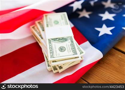 budget, finance and nationalism concept - close up of american flag and dollar cash money packets