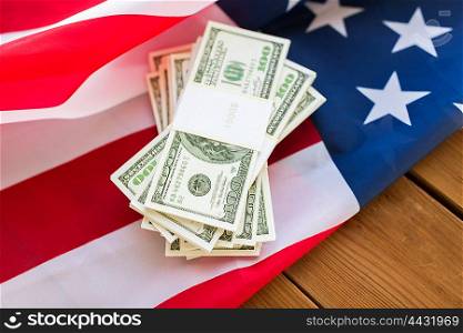 budget, finance and nationalism concept - close up of american flag and dollar cash money packets