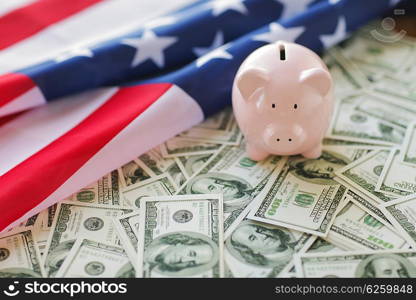 budget, finance, saving and nationalism concept - close up of american flag, piggy bank and dollar cash money