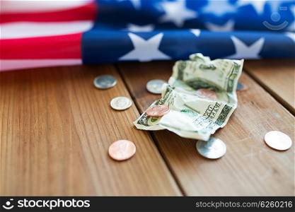 budget, money, finance, financial crisis and nationalism concept - close up of american flag and cent coins with crumpled dollar banknote on wood