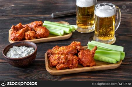 Buffalo wings with celery stalks, blue cheese dip and glass mugs of beer