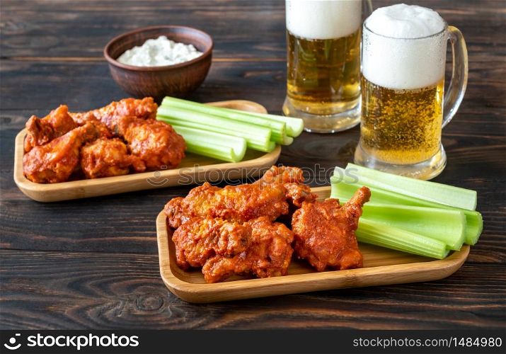 Buffalo wings with celery stalks, blue cheese dip and glass mugs of beer