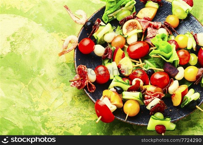 Buffet appetizer of shrimps, jamon, fruits and vegetables on wooden skewers.Copy space. Easy snack from vegetables, fruits, meat and seafood