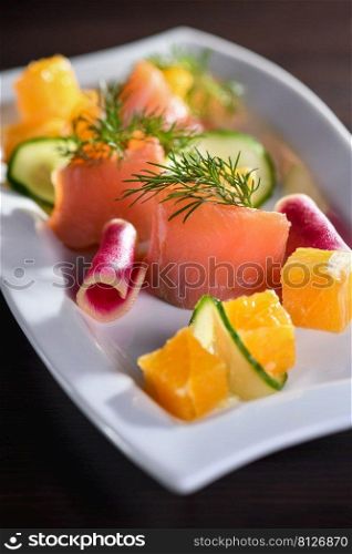 Buffet serving of pickled salmon slices with radish, cucumber and orange cubes