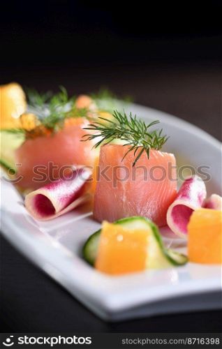  Buffet serving of pickled salmon slices with radish, cucumber and orange cubes
