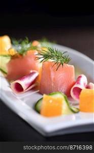 Buffet serving of pickled salmon slices with radish, cucumber and orange cubes