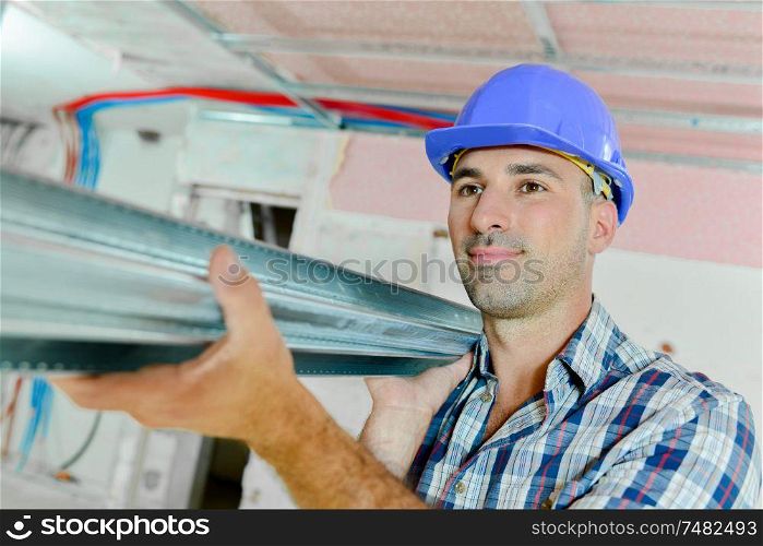 Builder carrying metal lengths on his shoulder