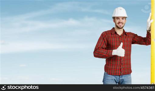 Builder checking spirit level. Engineer man in helmet outdoor using level