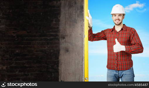 Builder checking spirit level. Engineer man in helmet outdoor using level