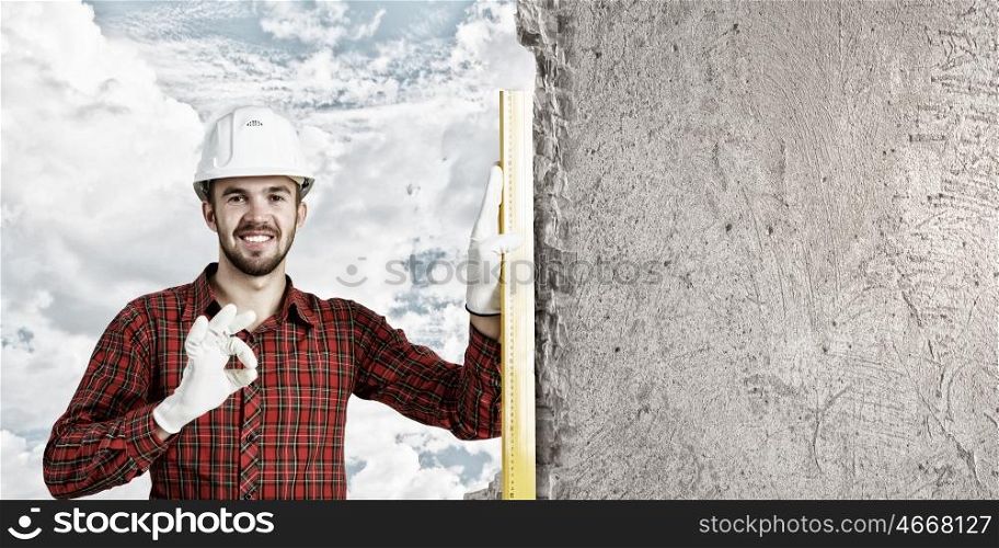 Builder checking spirit level. Engineer man in helmet outdoor using level