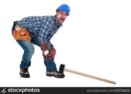 Builder dropping hammer on foot