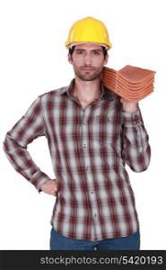 Builder holding stack of roof tiles