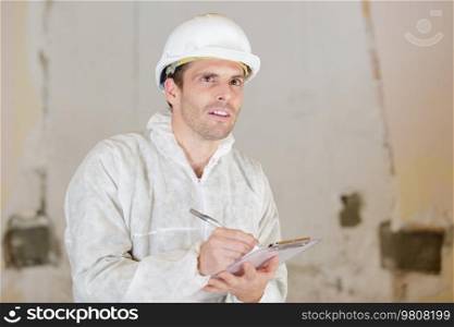 builder in protected cloths writing on clipboard