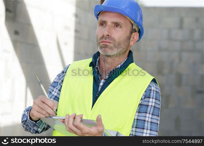 builder in vests writing on clipboard