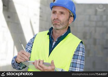 builder in vests writing on clipboard