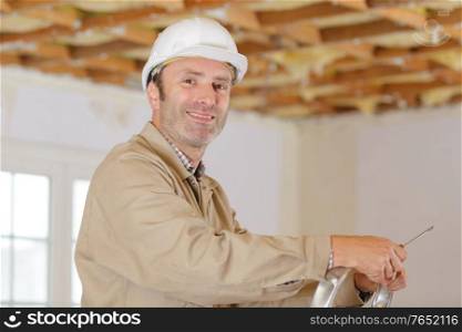 builder man in helmet next to ladder