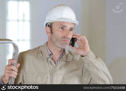 builder on the phone by a ladder