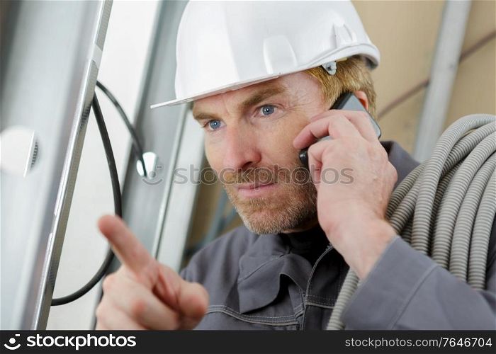 builder on the phone with equipment indoors