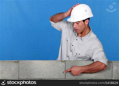 Builder pointing at a block wall
