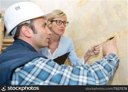 builder points at wall while supervisor looks