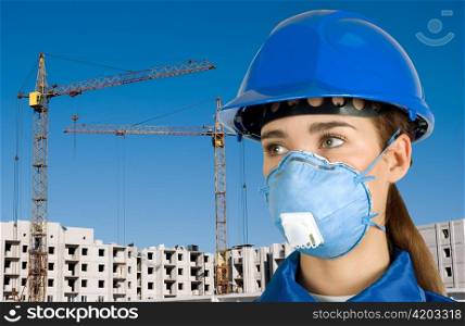 Builder pretty girl at helmet on a building background