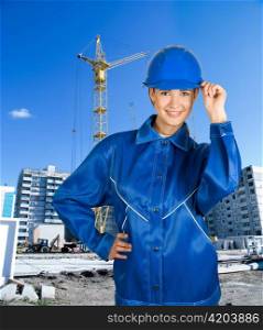 Builder pretty girl at helmet on a building background