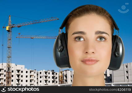 Builder pretty girl at safety earphone on a building background