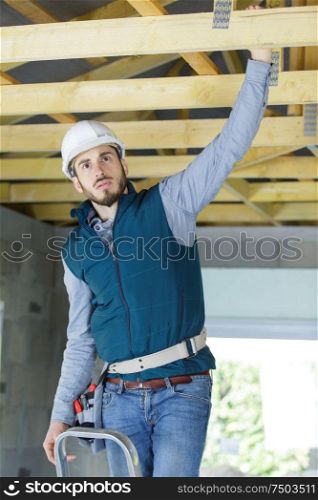 builder reaching up to roof timber