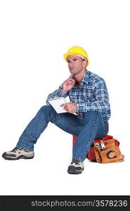 Builder sat on tool box thinking