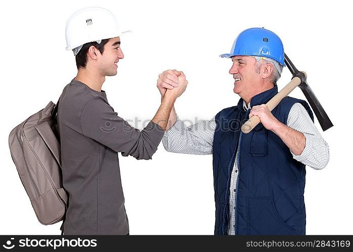 Builder shaking hands with young apprentice