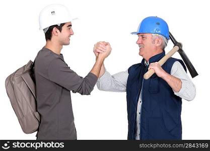 Builder shaking hands with young apprentice