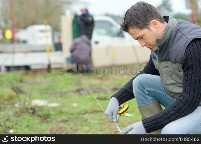 Builder taking measurements in the garden