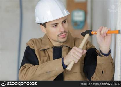 builder using a hammer to remove plaster from a wall