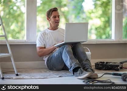 Builder using laptop on floor