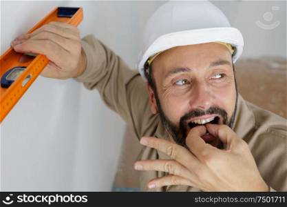 builder using spirit level and whistling with his fingers