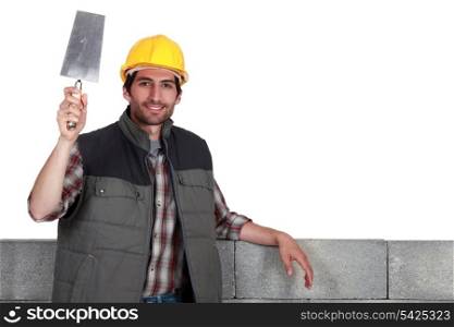 Builder with a bucket trowel and block wall
