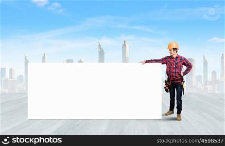 Builder with banner. Young builder man in hardhat holding white blank banner